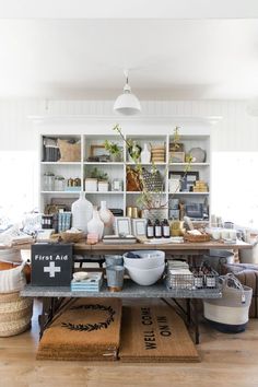 a table with bowls and baskets on it in a room filled with shelves full of items