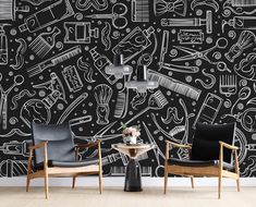 two chairs and a table in front of a black wall with white drawings on it