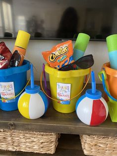 several buckets filled with candy and other items sitting on a shelf next to each other