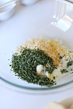 a glass bowl filled with cheese and herbs