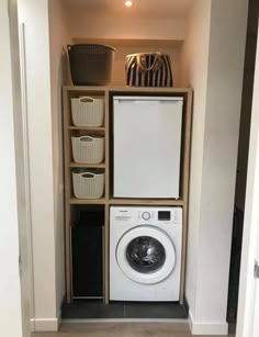 a washer and dryer sitting in a small room next to a shelf with baskets