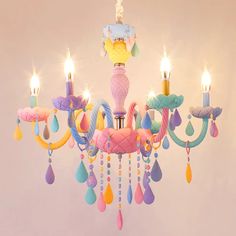 a chandelier that has several candles on it and colorful decorations hanging from the ceiling