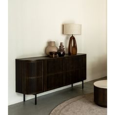 a sideboard with two vases on it and a lamp in the corner next to it