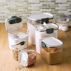 four containers with lids are sitting on a wooden table next to eggs and other food