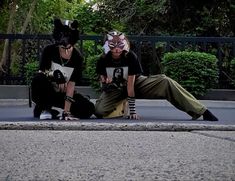 two people in animal masks sitting on the ground