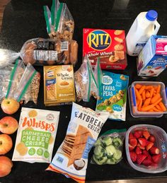 an assortment of food is laid out on a counter top, including apples, carrots, cucumbers and other foodstuffs