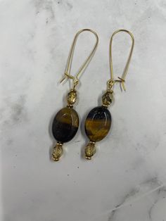 🐯 Tiger Eye Earrings with 22k Gold 🐯 Elevate your style with these exquisite Tiger Eye Earrings set in 22k gold. Handcrafted with stunning tiger eye gemstones, these earrings capture the rich, earthy tones and natural beauty of the stones, beautifully complemented by the luxurious 22k gold setting. Perfect for adding a touch of elegance and sophistication to any outfit, these earrings are a must-have for any jewelry lover. ✨ Features: Design: Beautiful tiger eye gemstones set in elegant 22k go Gold Gemstone Drop Crystal Earrings, Elegant Yellow Drop Earrings, Gold Gemstone Drop Danglers, Elegant Yellow Earrings With Natural Stones, Yellow Gold Teardrop Earrings With Natural Stones, Gold Dangle Gemstone Linear Earrings, Gold Gemstone Linear Earrings Gift, Gold Linear Gemstone Earrings As A Gift, Gold Earrings With Natural Stones For Gift