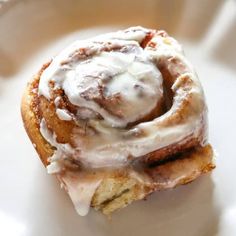 a cinnamon roll with icing on a white plate