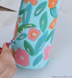 someone is painting a vase with flowers on it