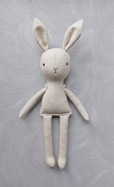 a white stuffed rabbit is hanging on the wall with its head turned to the side