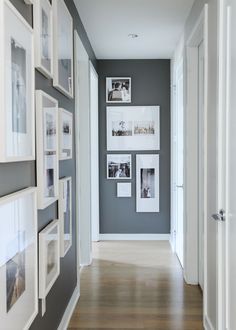 a long hallway with pictures on the wall and wooden flooring in front of it