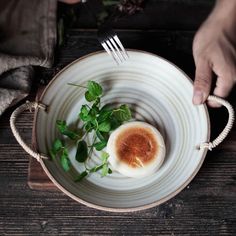 a person is holding a fork and knife over a plate with an egg on it