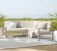 a white couch sitting on top of a wooden floor next to a plant filled area