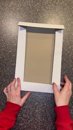 two hands are holding up a white frame