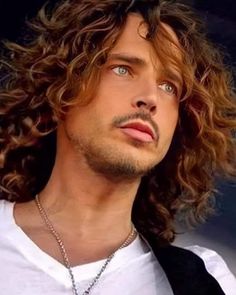 a man with long curly hair wearing a white shirt