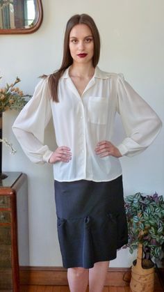 "Beautiful classic detailed vintage blouse by Jack Mulqueen. Vintage is 1980s or 1990s. Voluminous full sleeves, finely gathered at shoulders, and at the 1 1/2\" cuffs. Tiny mother of pearl buttons at cuffs. Yoked shoulders and back. Gathered at front yoke. Single patch pocket with eight rows of top stitching detail. White V neck notched collar with five rows of top-stitching. Top stitching down the front with four tiny mother of pearl buttons. Semi sheer ivory polyester crepe fabric. Labelled: Formal Long Sleeve Blouse With Gathered Sleeves, Vintage Bishop Sleeve Formal Blouse, Vintage Bishop Sleeve Blouse For Formal Occasions, Classic Fitted Blouse With Gathered Sleeves, Classic Long Sleeve Tops With Gathered Sleeves, Classic Long Sleeve Top With Gathered Sleeves, Vintage Fitted Blouse With Gathered Sleeves, Classic Long Sleeve Tops With Blouson Sleeves, Classic Blouse With Balloon Sleeves And Button Cuffs