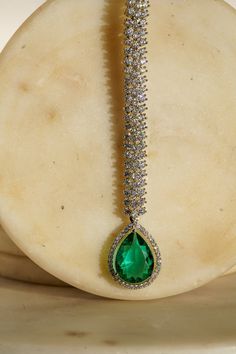 Enhance your elegance with the Safi Diamanté Accent Maang Tikka, a radiant piece crafted in a rhodium-plated silver finish. Available in stunning emerald green or sapphire blue, this exquisite maang tikka features a paved setting with glistening white diamante AD stones complemented by teardrop-shaped stones in your chosen hue. Its smaller size ensures a flattering fit for all face sizes, designed perfectly to complement our Sharmine necklace set. Key Features: Elegant Design: Paved setting with Emerald Maang Tikka, Fine Jewelry For Evening In Green, Fine Green Jewelry For Evening, Fine Green Jewelry For Evening Wear, Emerald Drop Jewelry With 17 Jewels, Exquisite Teardrop Jewelry For Party, Green Sparkling Stones Jewelry For Anniversary, Dazzling Green Jewelry For Gifts, Dazzling Green Jewelry For Gift