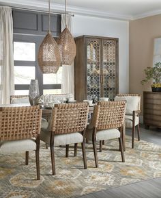 the dining room table is set with beige chairs and wicker baskets hanging from the ceiling