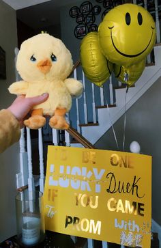 a person holding a stuffed animal in front of a sign that says, be lucky duck if you came to prom with two balloons