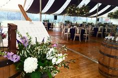 a wooden barrel filled with flowers on top of a hard wood floor next to tables