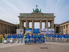 a group of people standing in front of a building with statues on either side of it