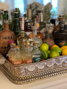 a tray filled with bottles and lemons on top of a counter next to other liquor bottles