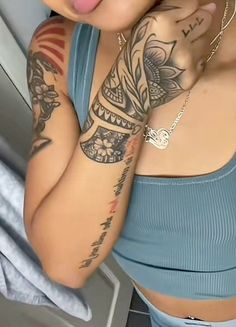 a woman with tattoos on her arms and chest sticking out her tongue to the camera