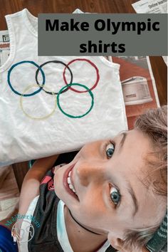 a young boy holding up a t - shirt with the olympic rings on it