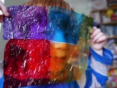 a person holding up a piece of plastic in front of their face with different colors on it