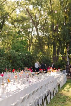 a long table is set up with flowers and wine glasses for an outdoor wedding reception