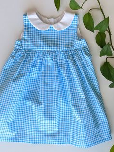 This 12-18 month blue and white gingham sleeveless dress is perfect for the summer season! It's finished off with a simple white collar and back button closures. This geranium dress pattern is used with permission and designed by Rae Hoekstra of made-by-rae.com. 12-18 Month Chest (in) - 19.5 Weight (lbs) - 22-27 Height (in) - 29-31 This dress pattern is available in many variations (size, fabric pattern, sleeves, no collar, etc.) just send me a message! Preppy Sleeveless Dress For Picnic, Preppy Sleeveless Summer Dress, Cute Sleeveless Spring Plaid Dress, Sleeveless Plaid School Dress, Plaid Sleeveless School Dress, Preppy Plaid Sleeveless Dress, Gingham Dresses For School In Spring, Sleeveless Summer School Dress, Plaid Summer Dress For School