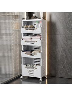 a white storage rack with five baskets on wheels in front of a marble wall and door