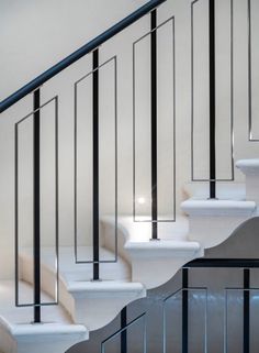 a white staircase with black handrails and glass railing