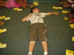 a young boy laying on the floor surrounded by post it notes and papers with words written in them