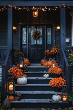 a front porch decorated for fall with pumpkins, mumbers and lanterns on the steps