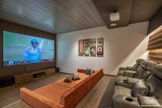 a living room with couches and a flat screen tv on the wall in front of it