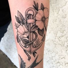 a black and white photo of an anchor with flowers on the side of her leg