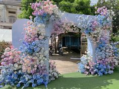 an archway decorated with blue, pink and white flowers