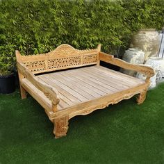 a wooden bed sitting on top of a lush green field