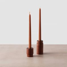 two tall candles sitting next to each other on a table