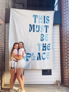 two girls hugging each other in front of a banner that says, this must be the place