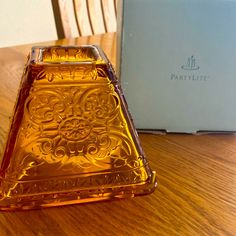 an orange glass vase sitting on top of a wooden table next to a box that says party lite