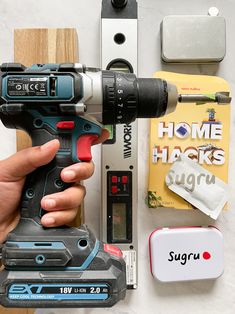 a person holding a drill in their hand next to some other tools and supplies on a table