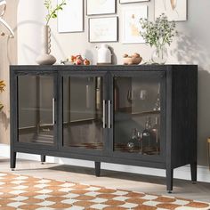 a black cabinet with glass doors and pictures on the wall