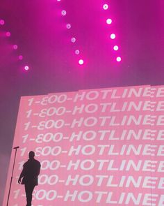 a man standing on top of a stage next to a giant screen with words all over it