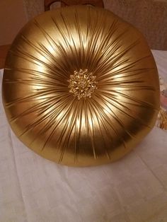 a large gold pillow sitting on top of a white tablecloth covered table next to a wooden chair