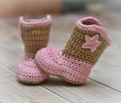 a pair of crocheted pink and brown baby booties sitting on top of a wooden floor