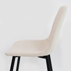 a white chair sitting on top of a black wooden floor next to a white wall