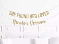 a white couch sitting next to a wall with a gold banner on it that says she found her lover nicole's version