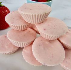 several pink cupcakes are stacked on top of each other with strawberries in the background